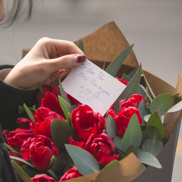 girl-reading-note-put-into-bouquet-red-tulips